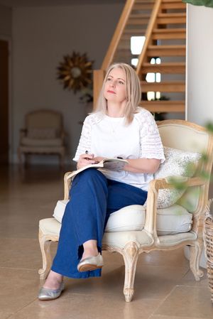 Person in white top and blue pants relaxing on elegant cream-colored chair.