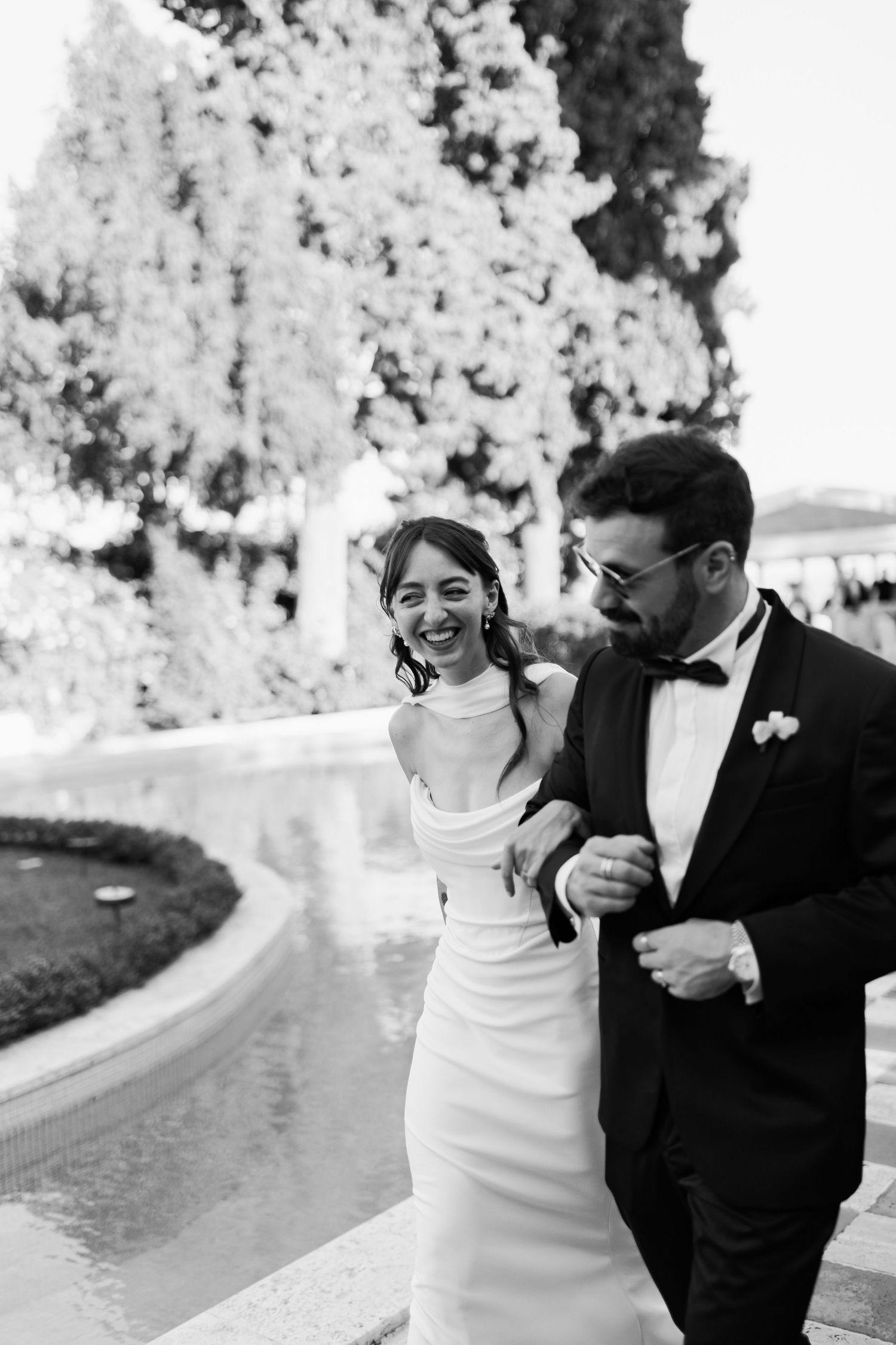 A happy couple shares joyful candid moments together outdoors in black and white photography.