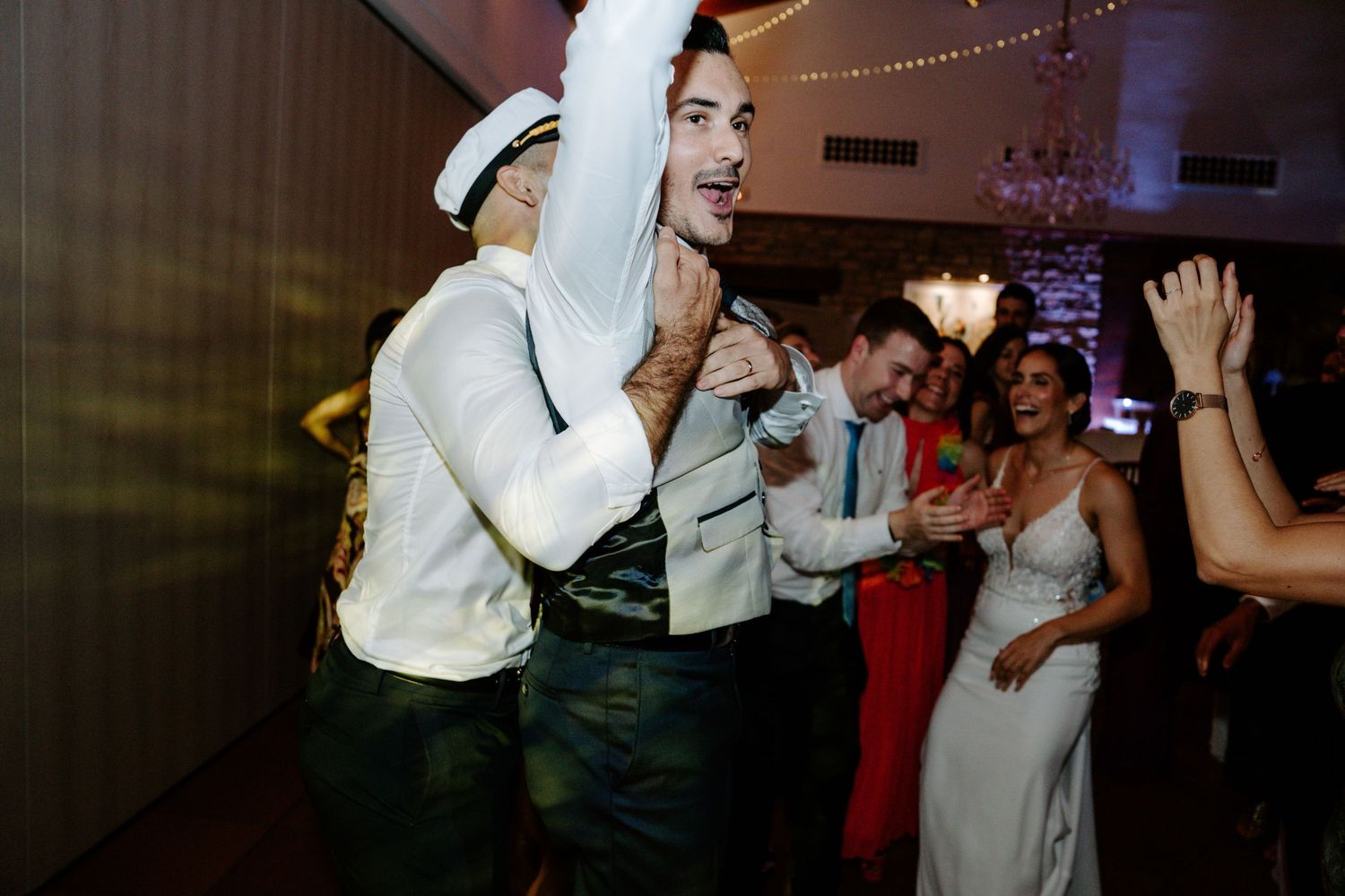Lively wedding reception dance party with guests enjoying themselves under string lights.