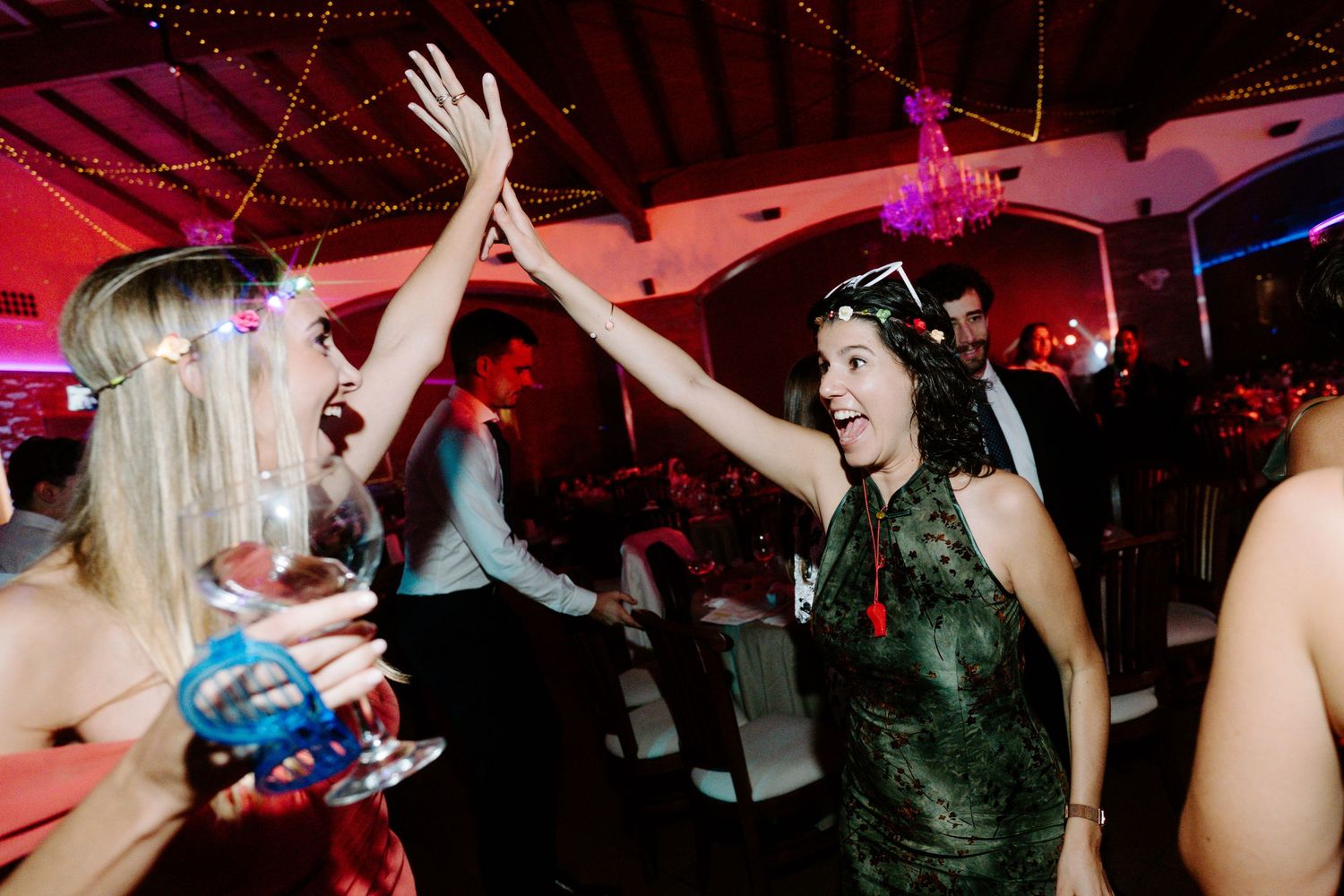 Silhouettes of party guests dancing under dramatic red lighting at a nighttime celebration.