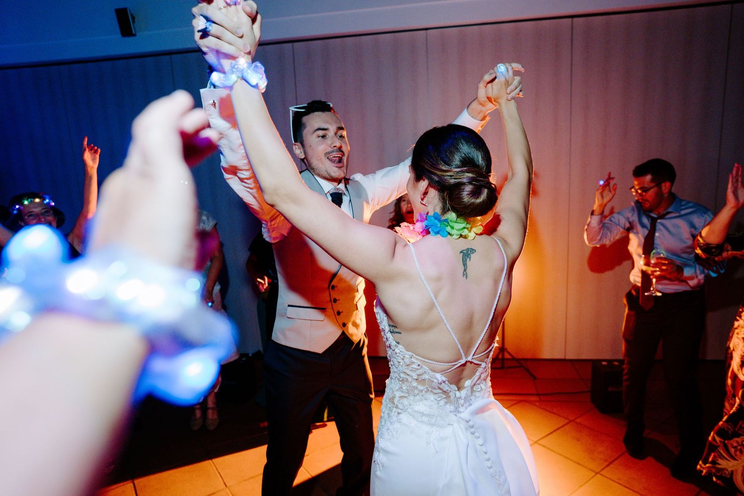 Pista de baile para la recepción de bodas con invitados celebrando bajo una espectacular iluminación azul y rosa.