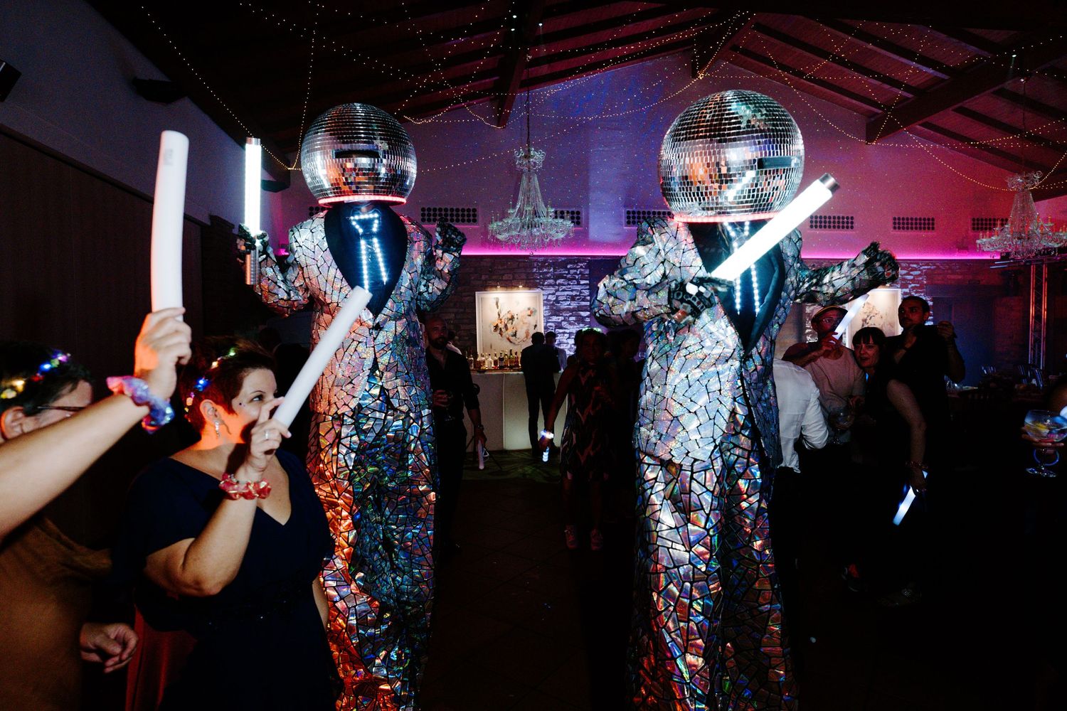 Wedding reception dance party with disco balls and colorful lighting creating an energetic atmosphere.