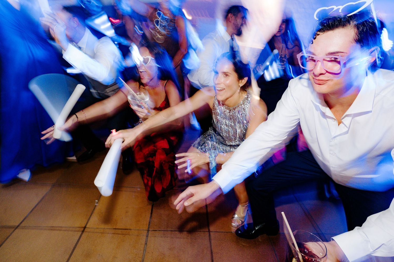 Guests dancing and celebrating at a wedding reception with vibrant blue lighting effects.