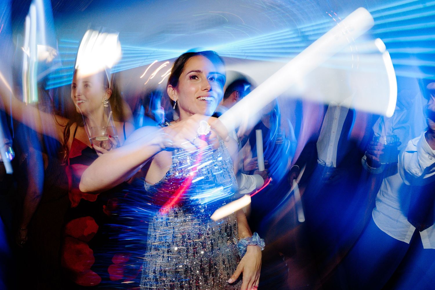 Dynamic dance floor scene with motion blur and blue lighting effects at a wedding celebration.