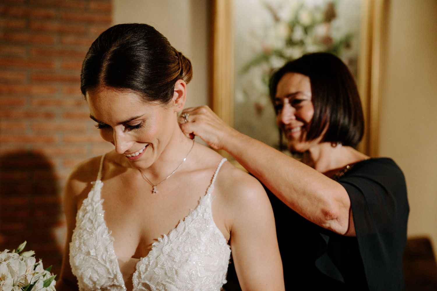 Intimate wedding moment captured in warmly lit hallway with brick accents.