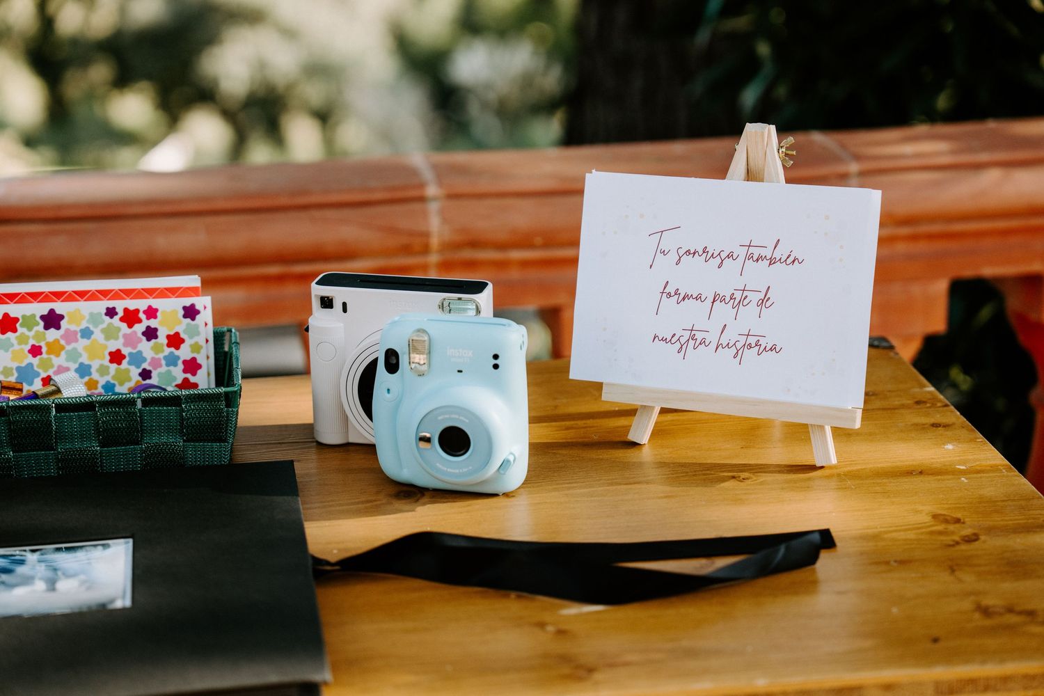 Wedding detail flatlay with cameras and decorative elements on wooden surface.