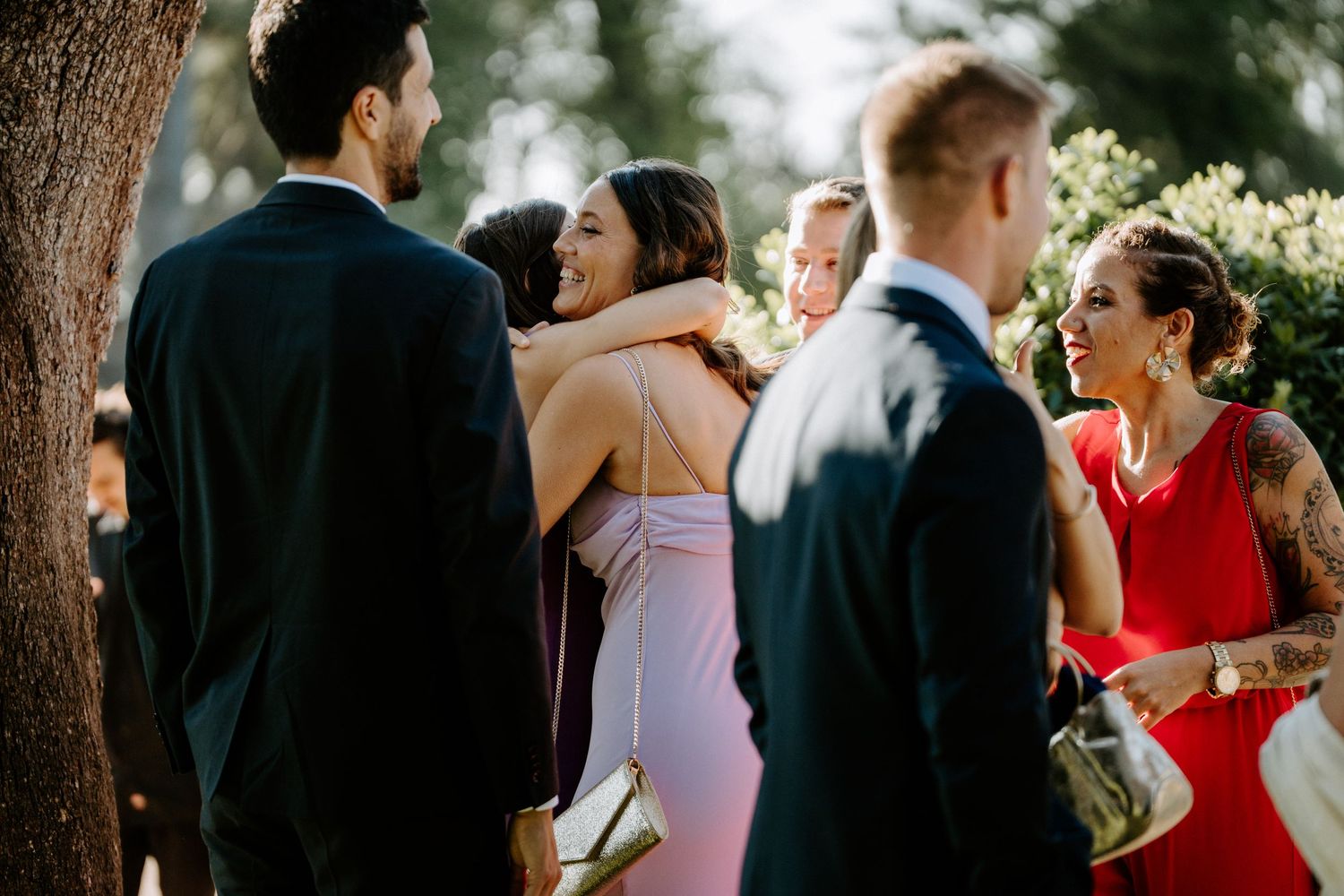 Wedding guests mingling during an elegant outdoor reception under trees.