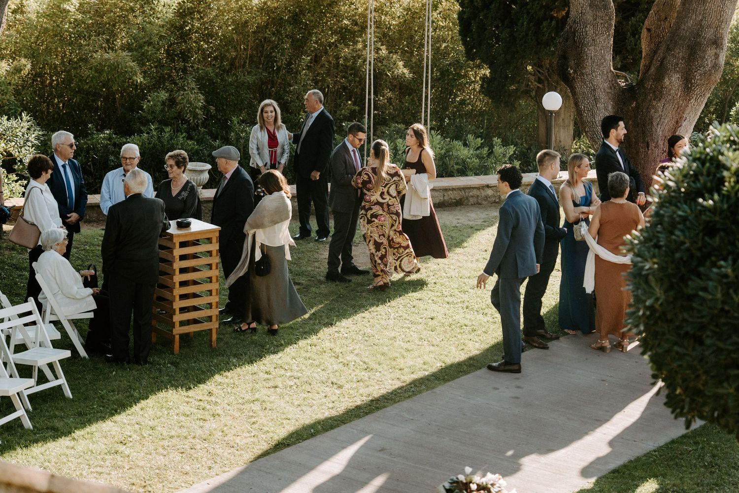 Outdoor wedding ceremony setup with white chairs and natural decor in a garden setting.