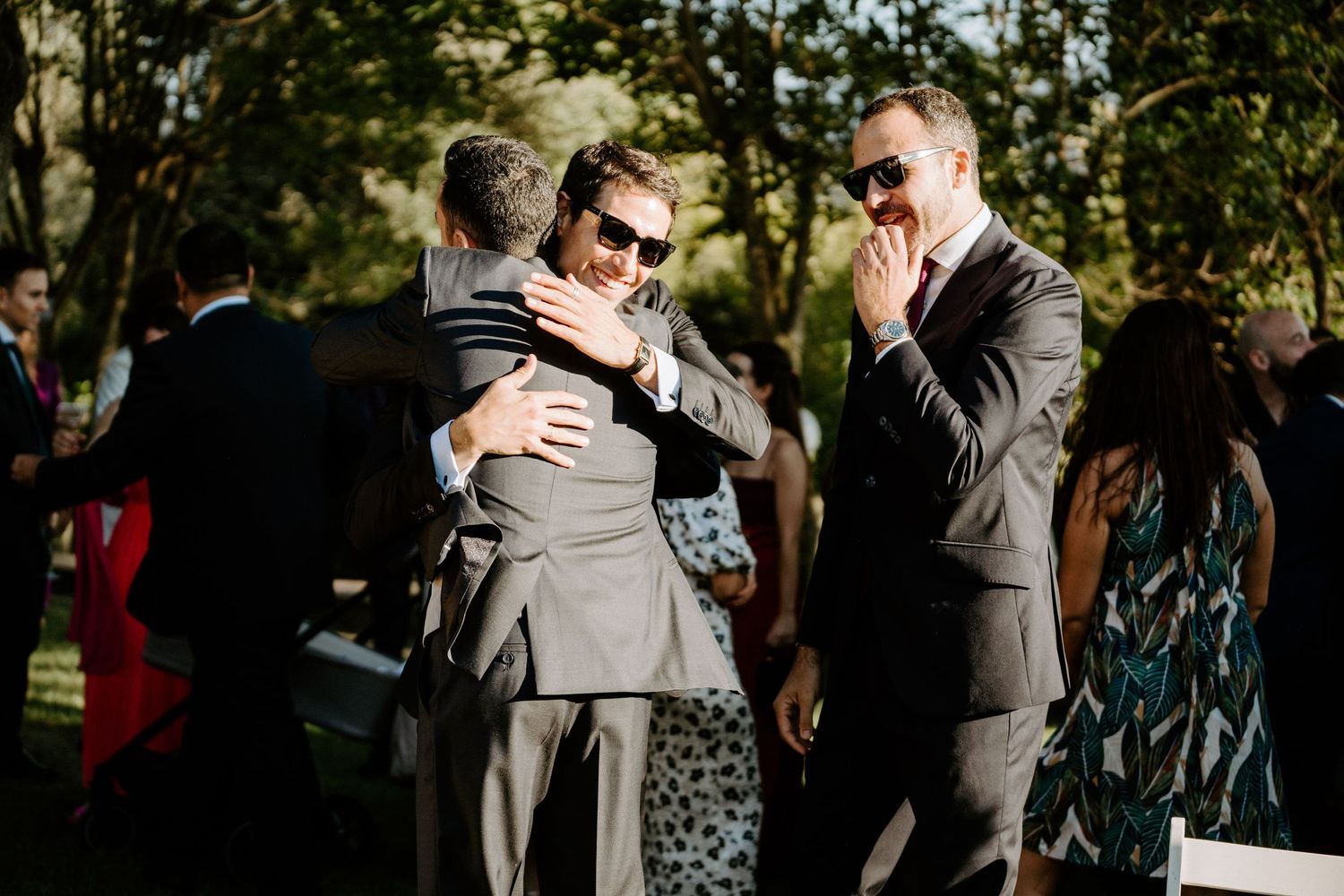 Wedding guests embracing and celebrating during an outdoor reception.
