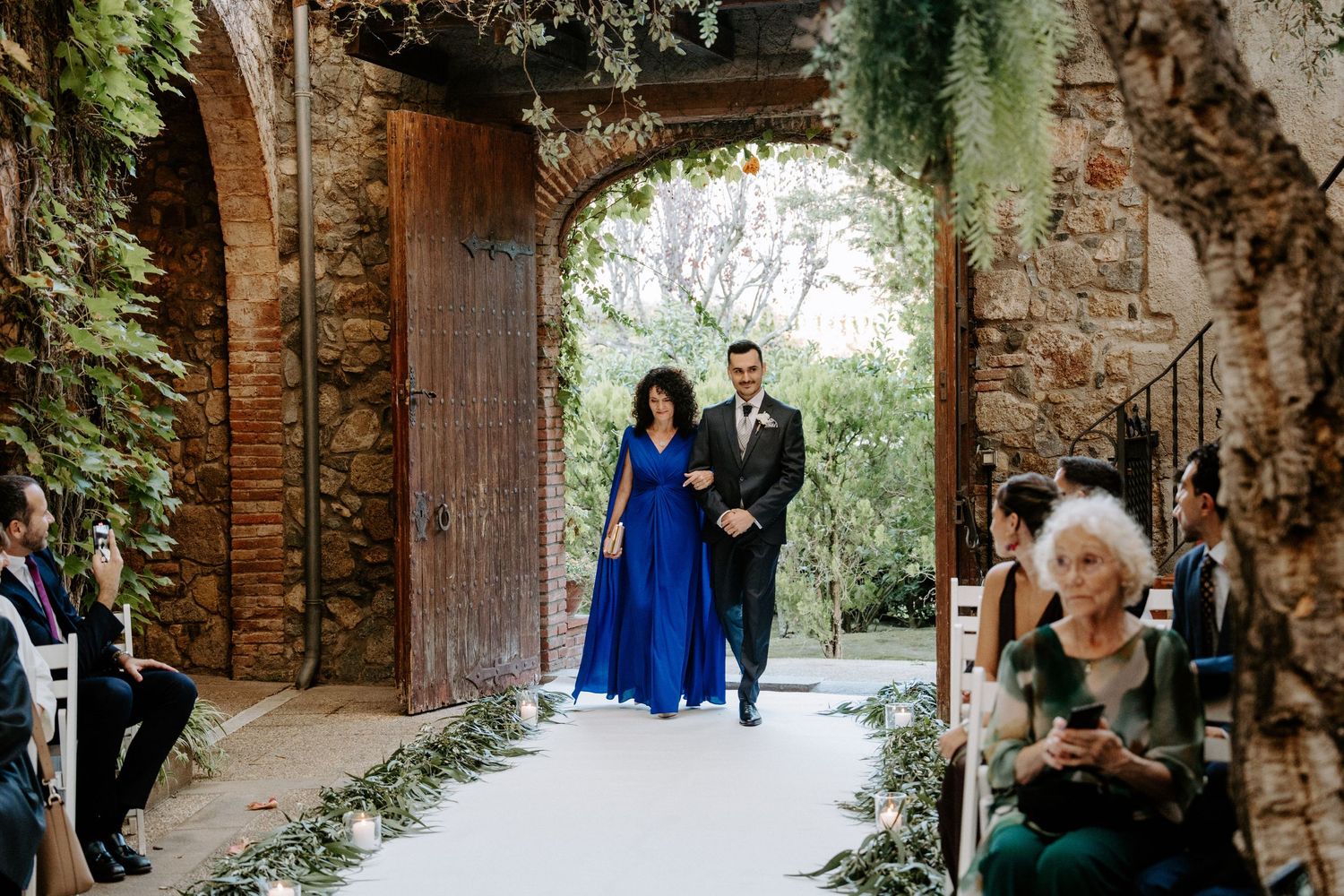 Stone archway corridor decorated with hanging greenery at an elegant wedding venue.