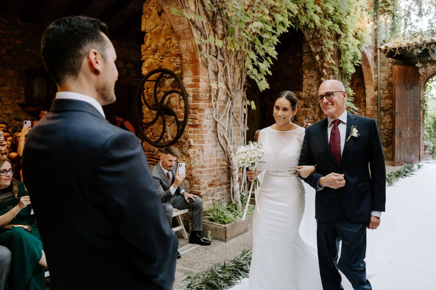 Elegant wedding ceremony taking place under historic stone archways.