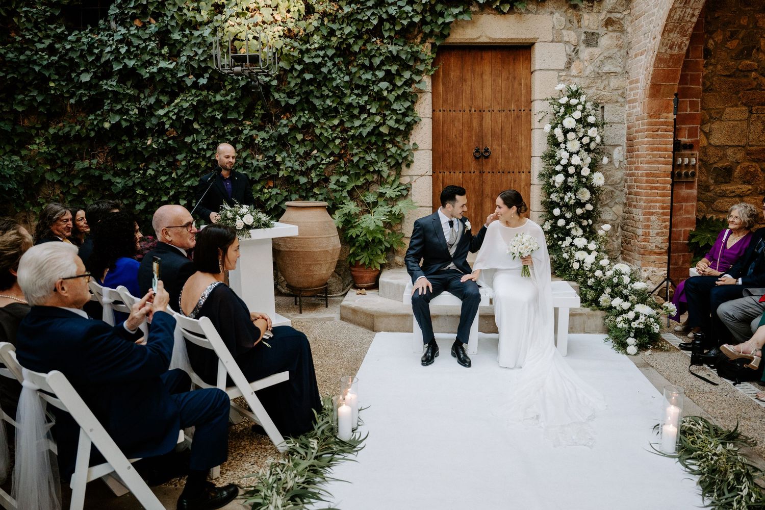 Wedding guests seated in white chairs during an intimate outdoor garden ceremony.