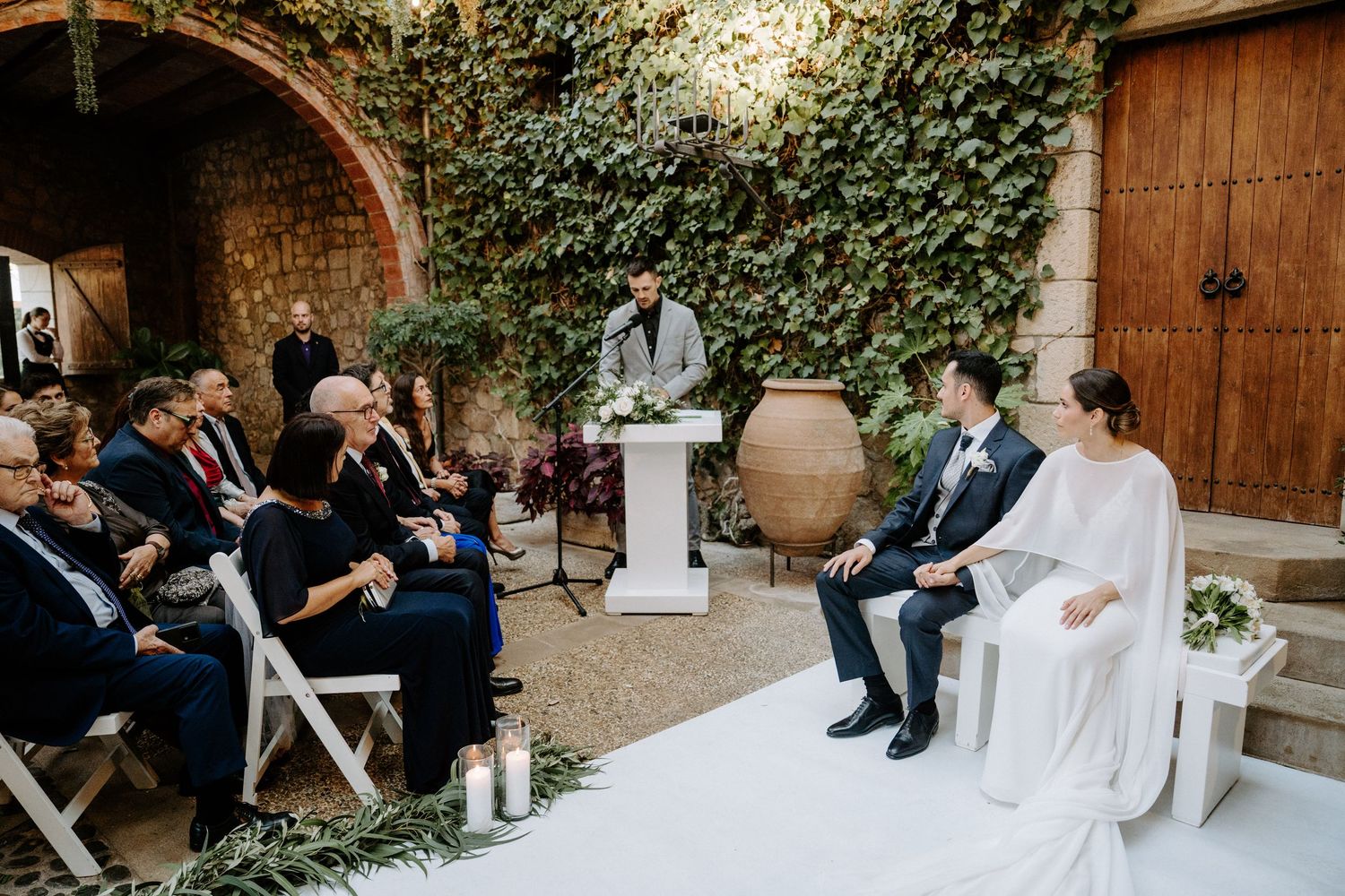 Wedding ceremony venue with ivy-covered walls and elegant white seating arrangements.