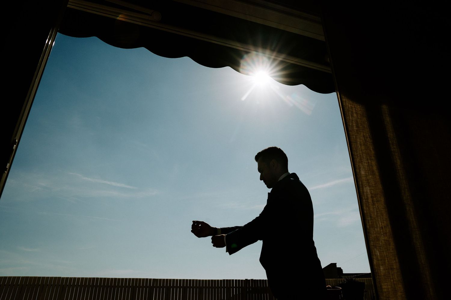 Silhouetted figures against bright sunlight through architectural frames.