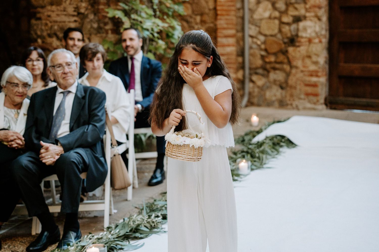 An emotional moment during a wedding ceremony in a rustic stone courtyard.