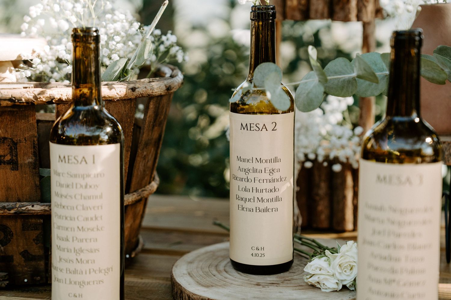 Wedding wine bottles with custom labels arranged on wooden surface.