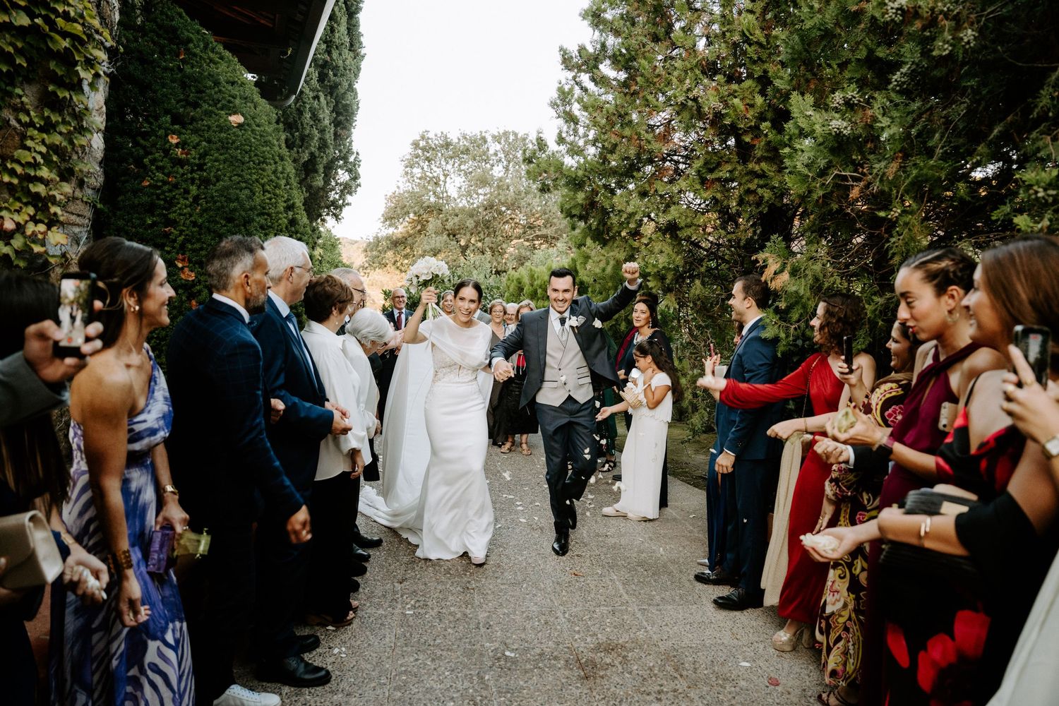Wedding guests celebrate along outdoor pathway during joyful reception.
