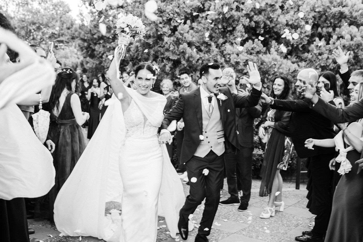 Black and white photo of wedding guests celebrating during outdoor reception.