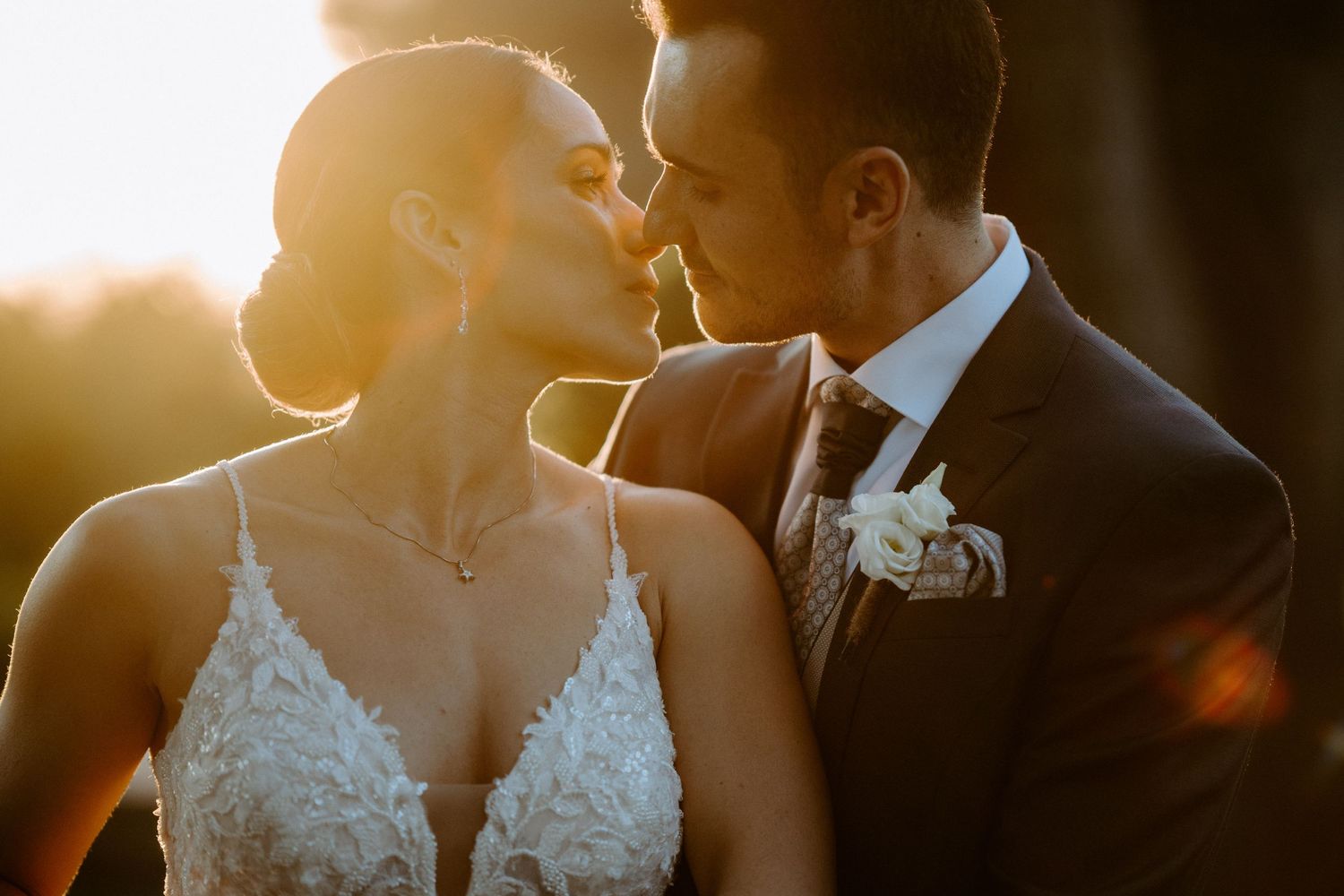 Intimate golden hour wedding portrait with dramatic backlighting and elegant formal attire.