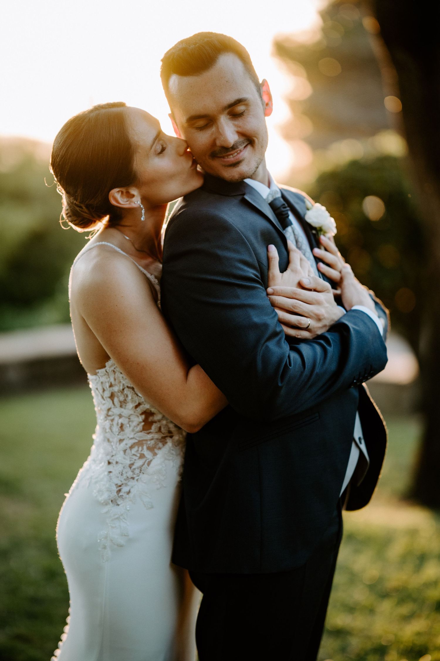 Tender moment captured during golden hour with bride in lace gown and groom in navy suit.