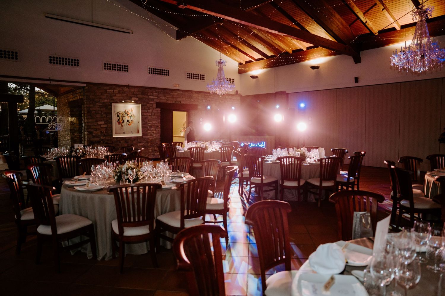 Indoor wedding venue with rustic wooden beams and elegant chandeliers.