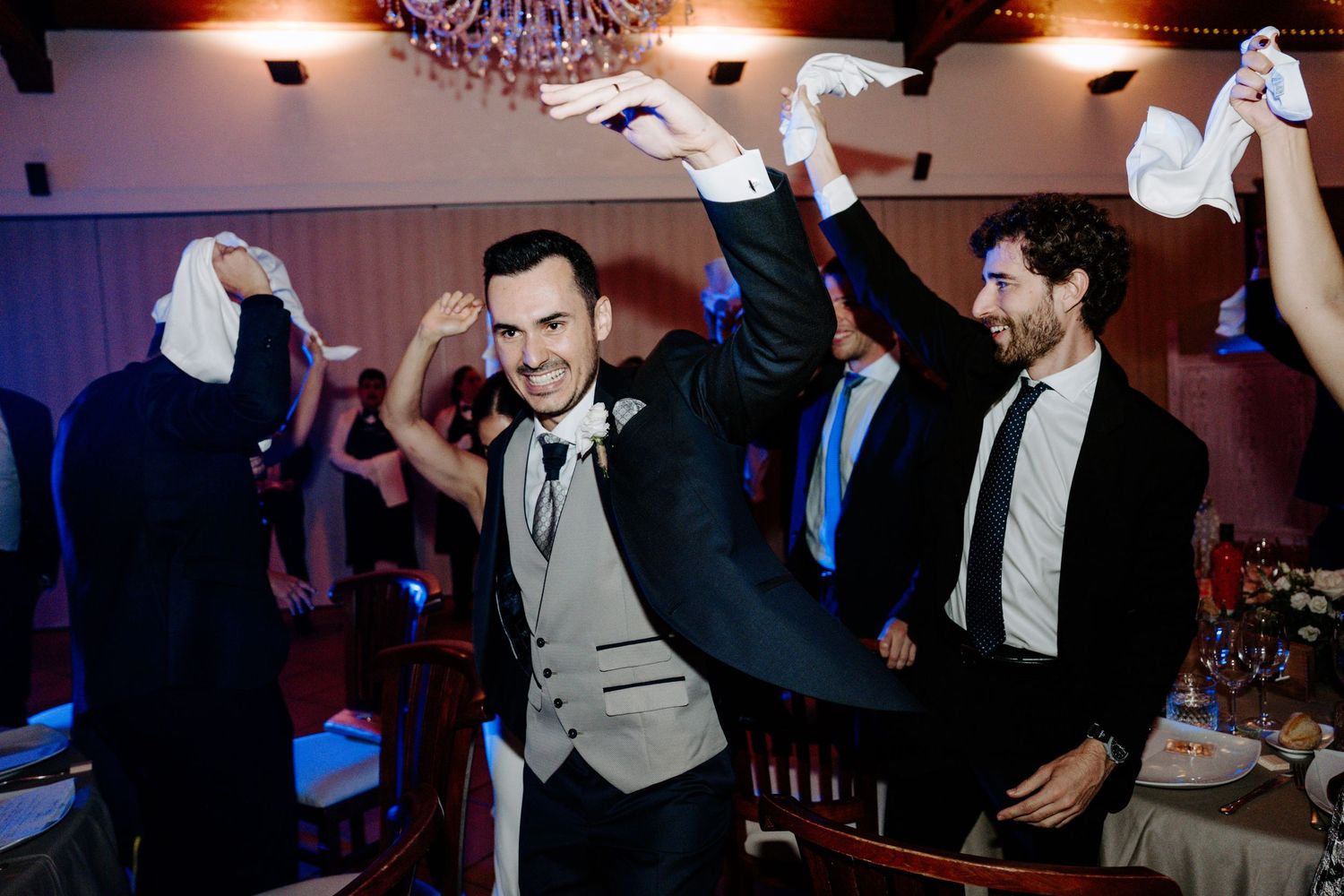 Lively wedding reception dance party with guests enjoying themselves under warm lighting.