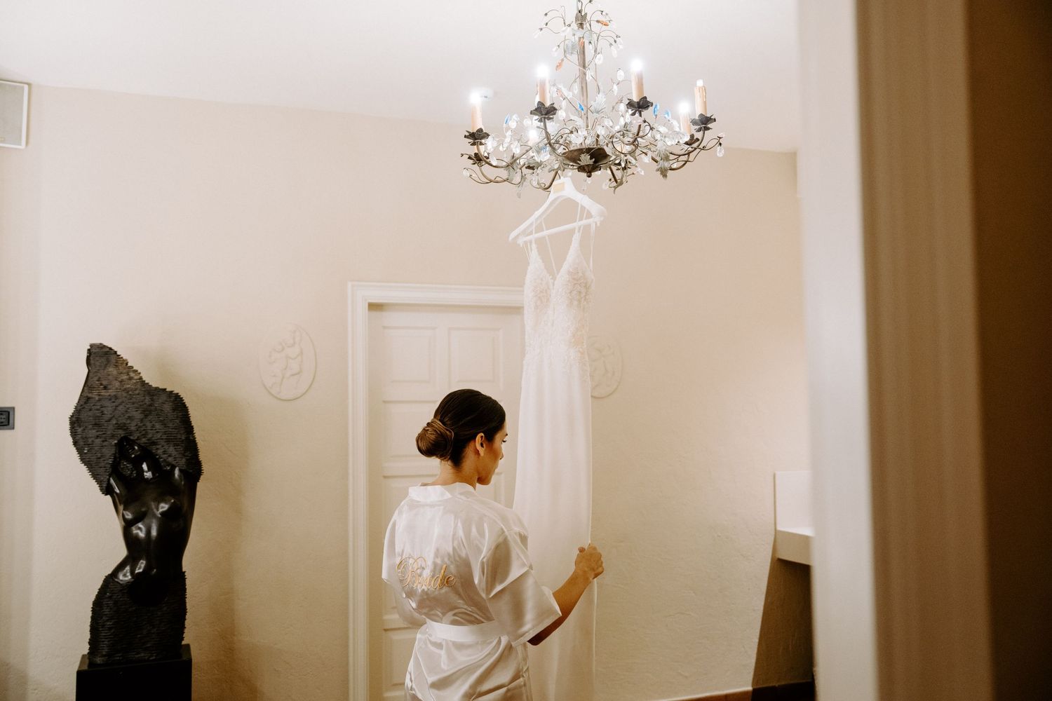 Elegant interior hallway with white walls and chandelier casting warm light and shadows.