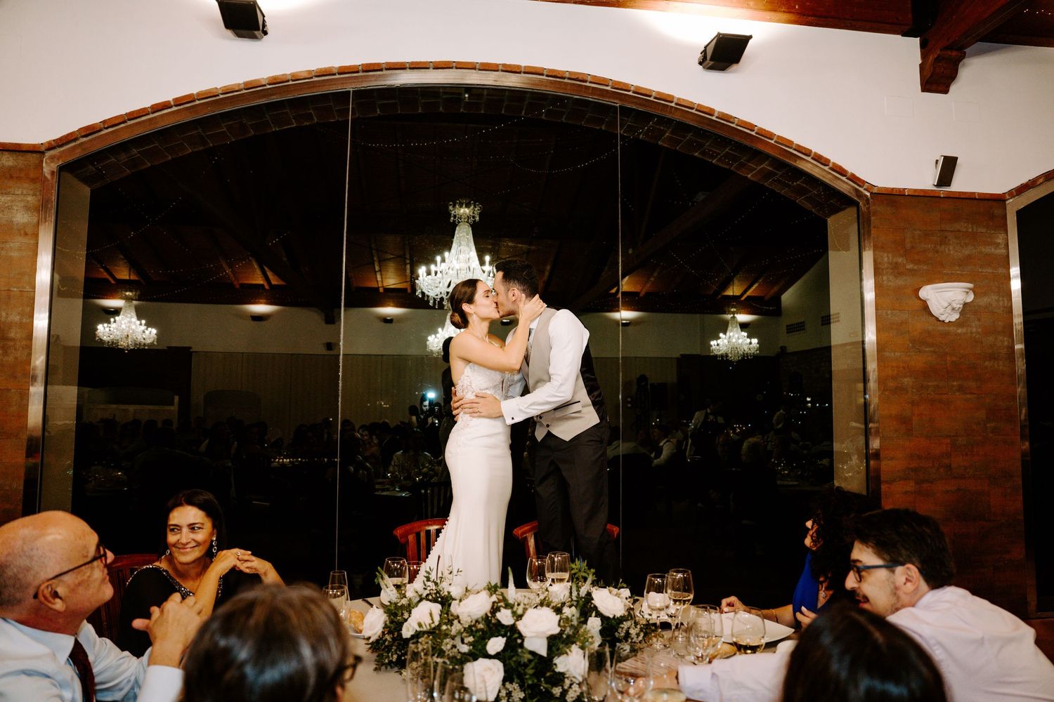 Rustic wedding venue with brick walls and hanging lights during evening reception celebrations.