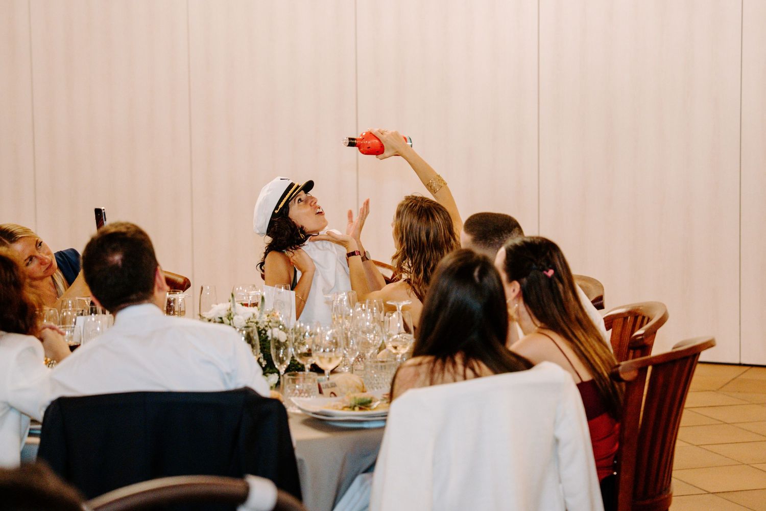 Wedding reception dining setup with elegant table settings and guests celebrating.