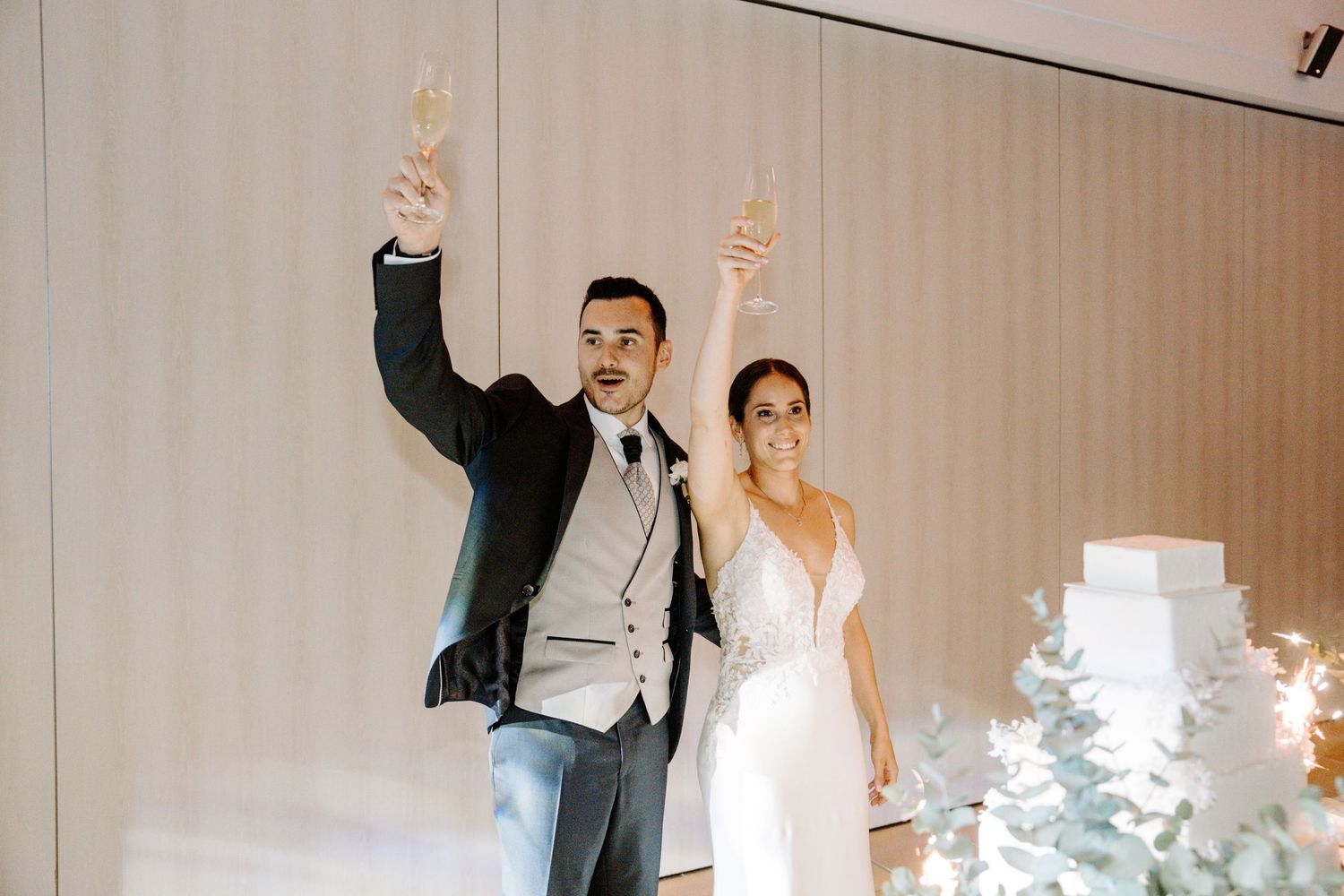 Wedding celebration with guests and couple dancing in an indoor venue with decorative lighting.