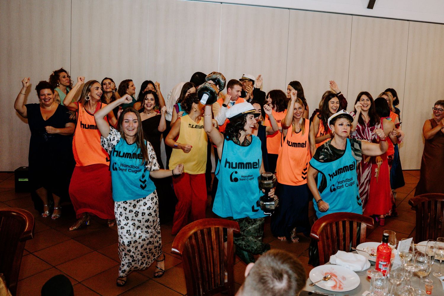 Wedding guests in bright colored attire dancing and celebrating at a reception.