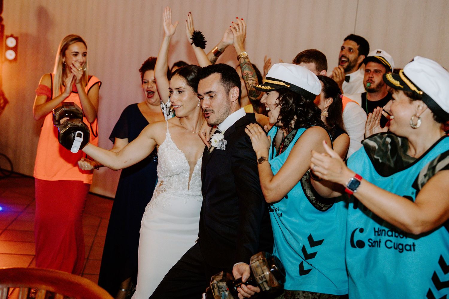 Energetic dance party at wedding reception with guests in turquoise and formal attire.