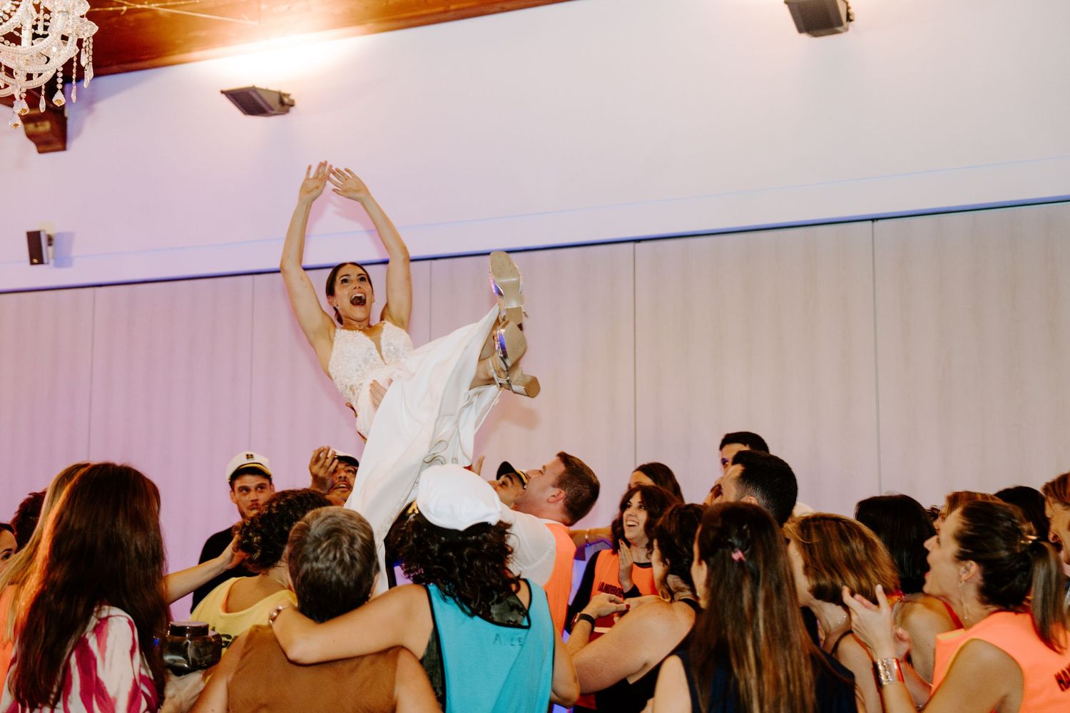 Wide angle view of wedding reception venue with guests dancing under warm lighting.