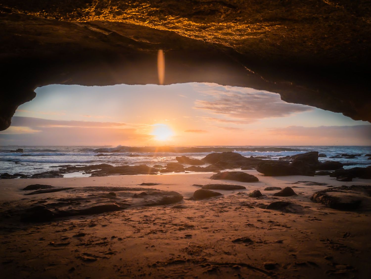 Stunning ocean cave view framing a vibrant sunset over coastal waters.