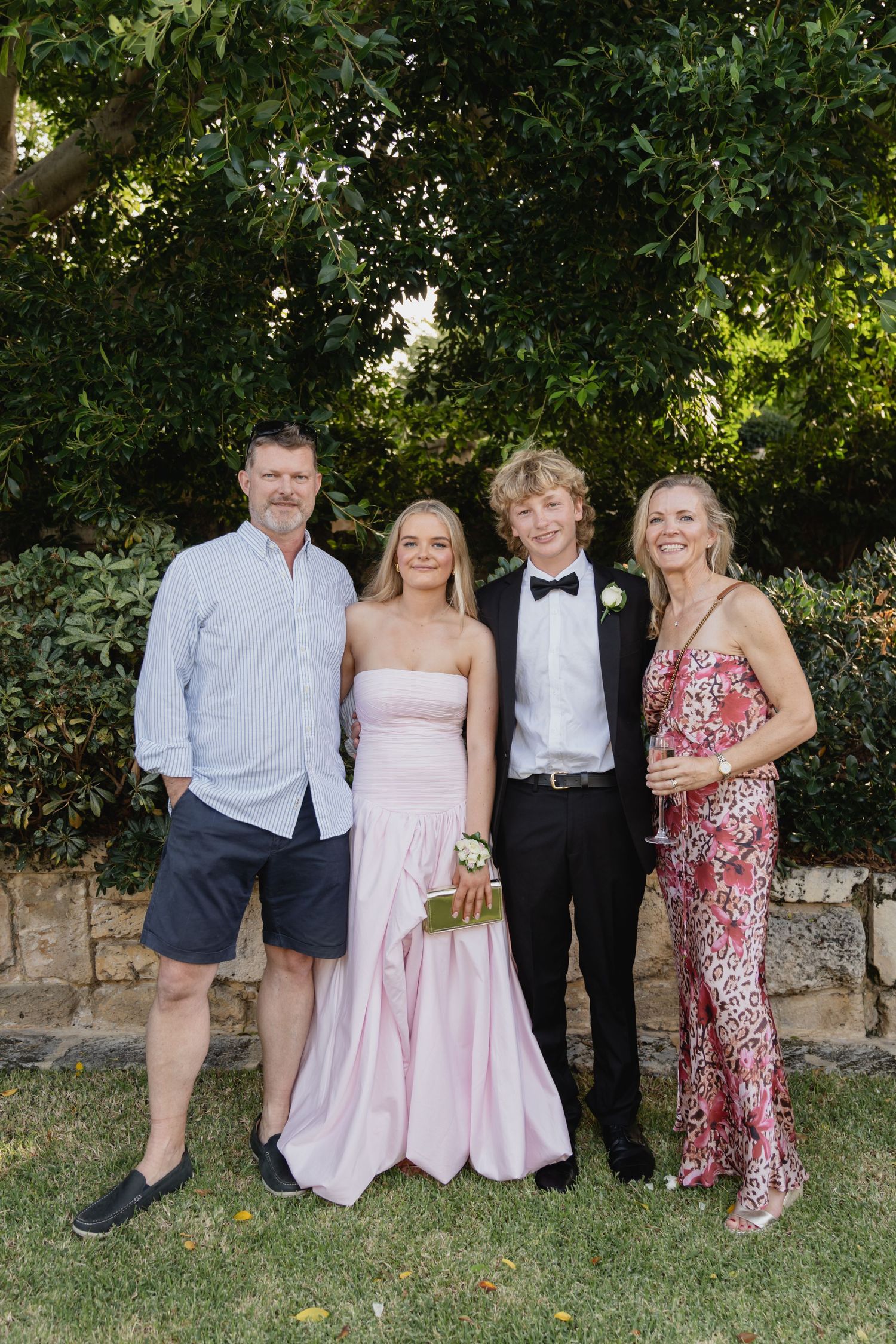 A group poses together outdoors for a formal event photo.