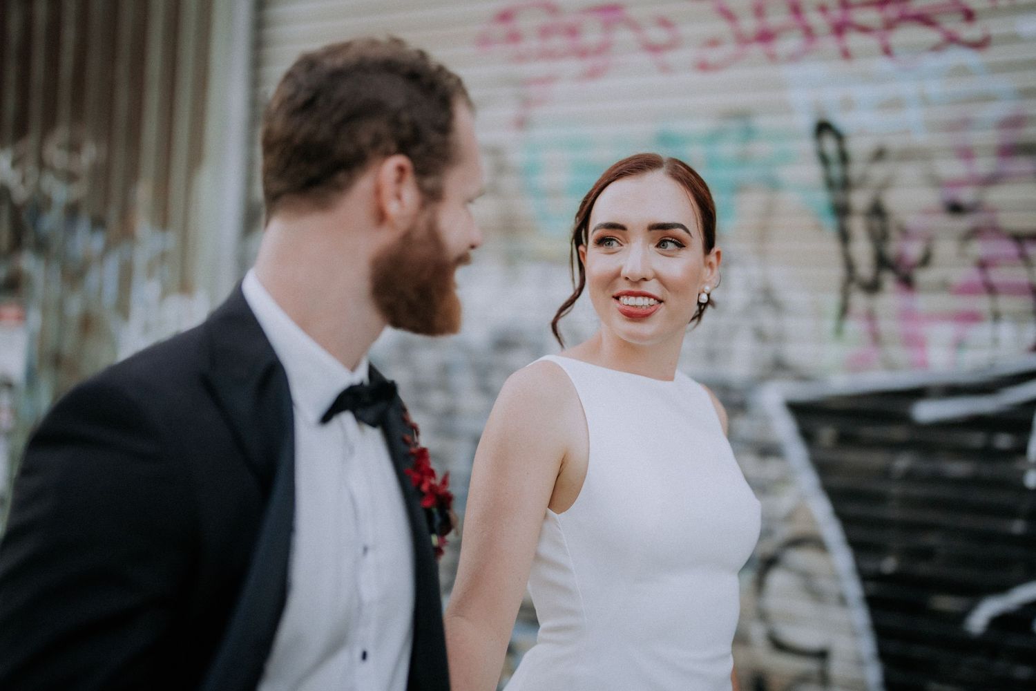 A romantic wedding photoshoot in front of a white building at sunset.