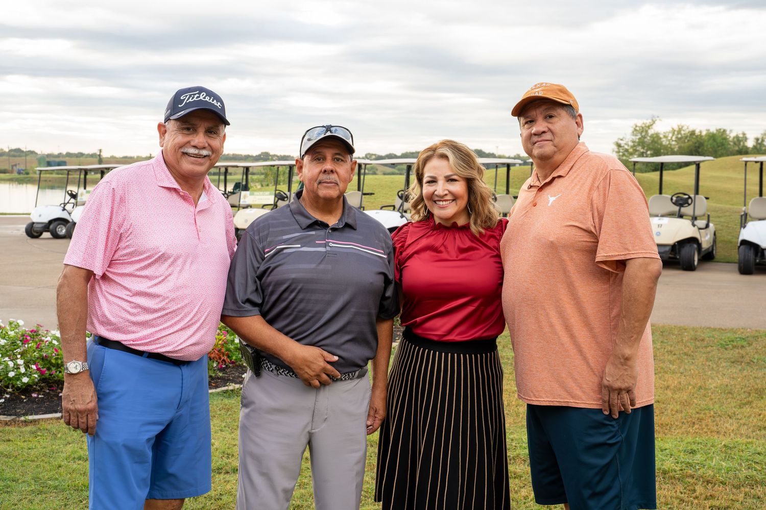 Group of golfers gathered on a golf course wearing casual attire during a tournament or social event.