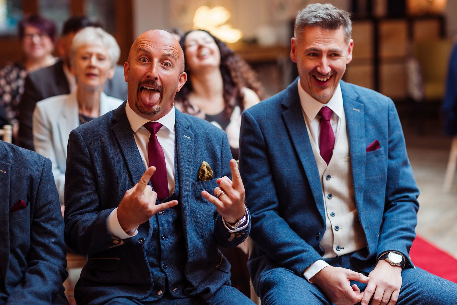 People in blue blazers and burgundy ties sitting in a row at a formal event.