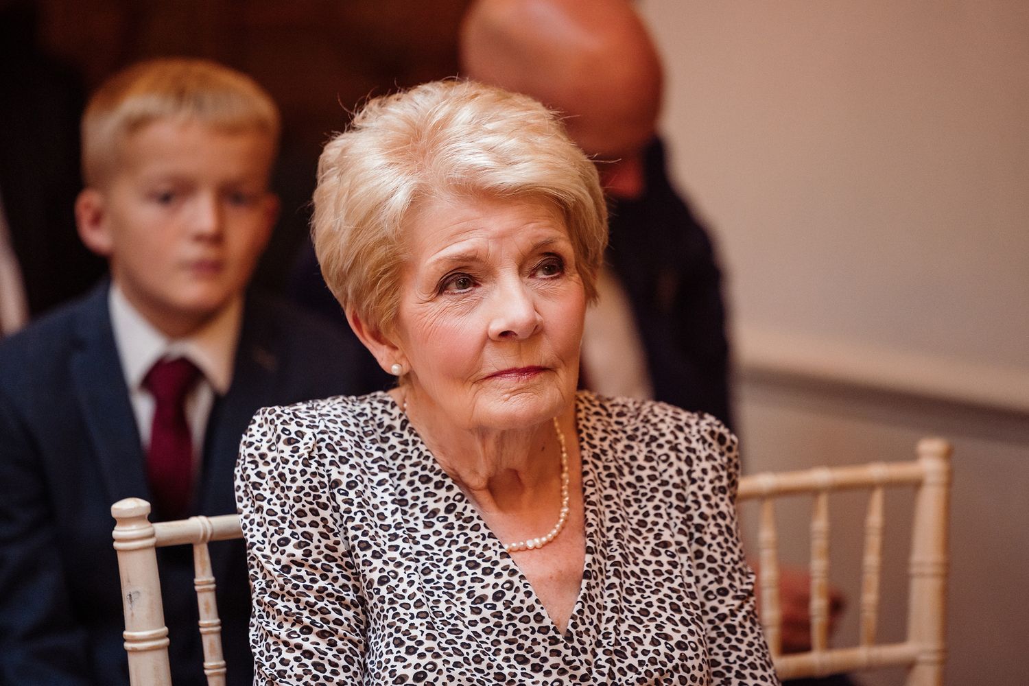 Woman in leopard print blouse seated at formal dinner event.