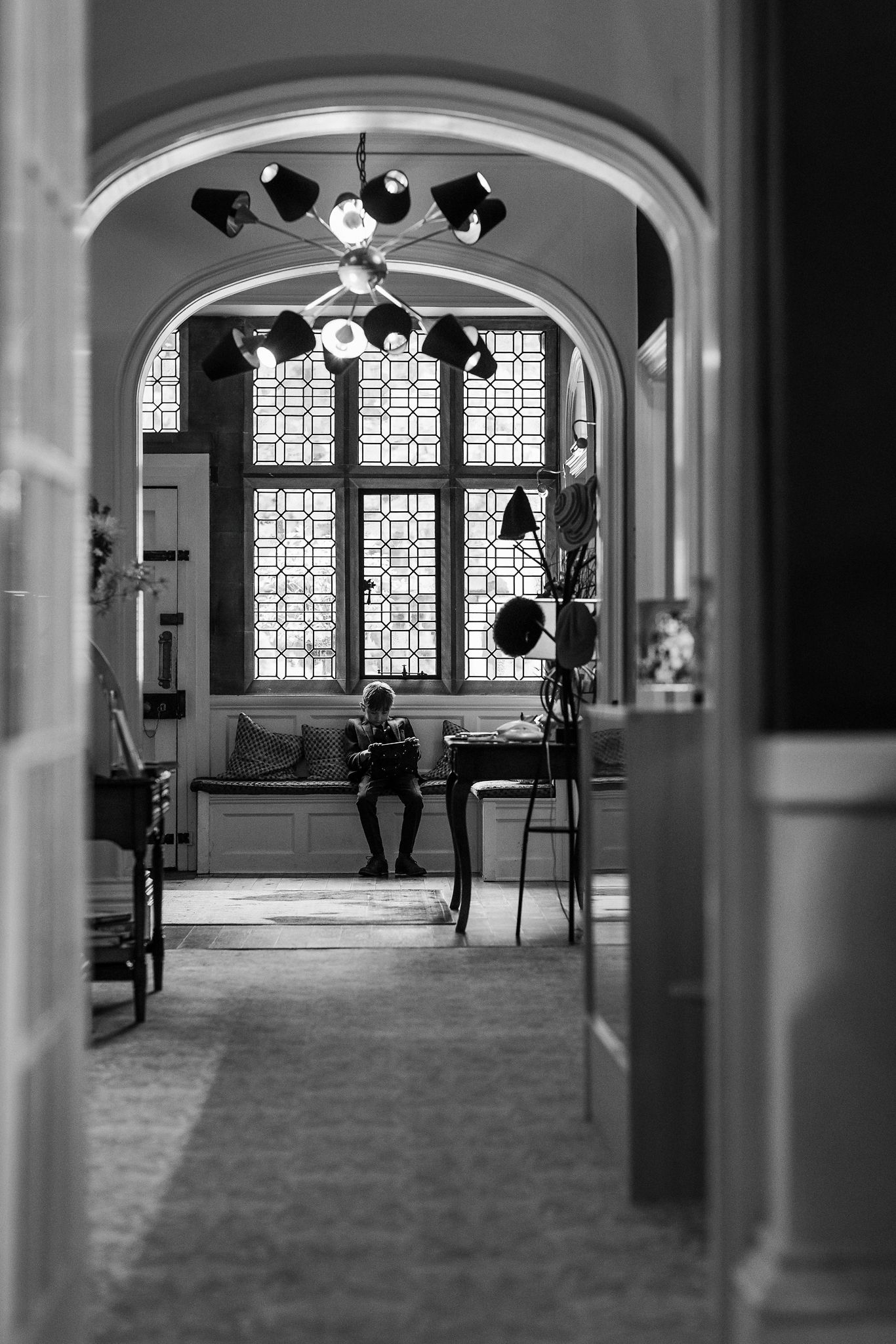 Black and white architectural interior showing a series of arches and decorative windows with silhouetted figures in motion.