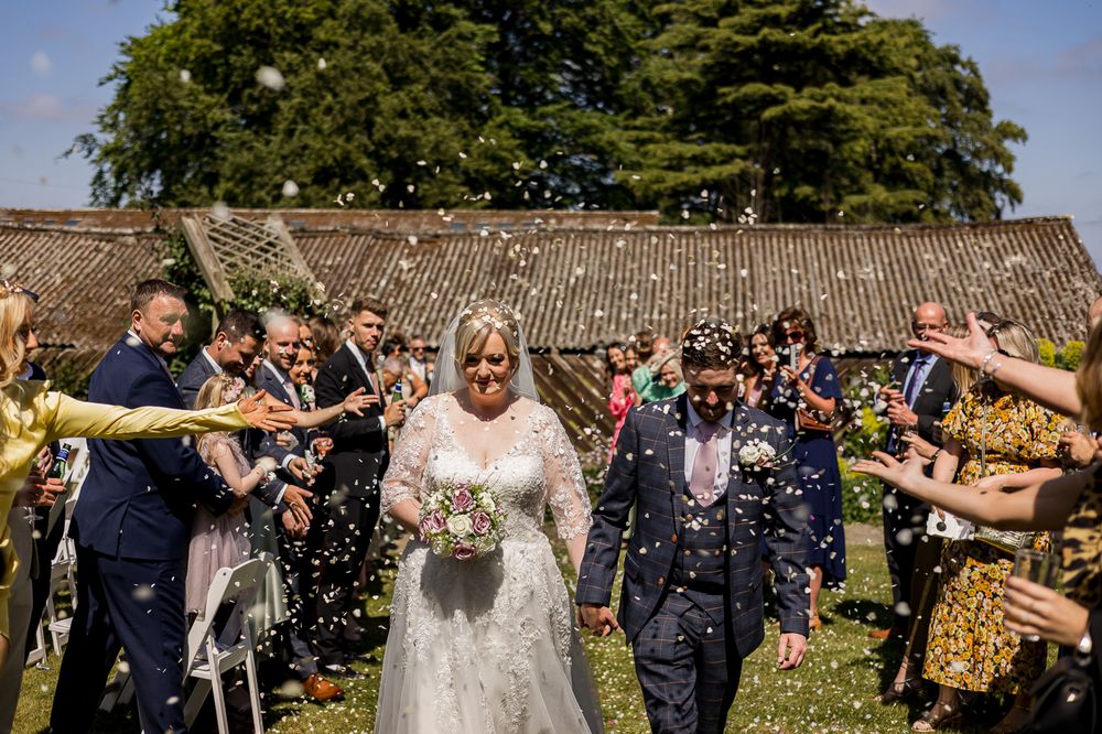 Wedding guests shower the couple with confetti in a joyful outdoor celebration.