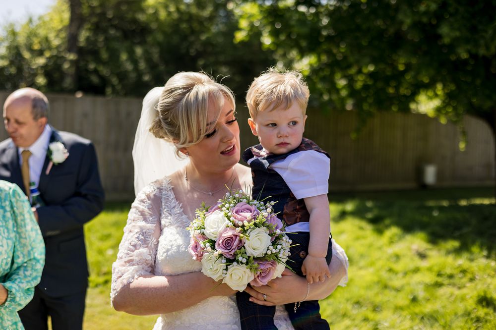 Wedding party members share candid moments in a sunny garden setting.