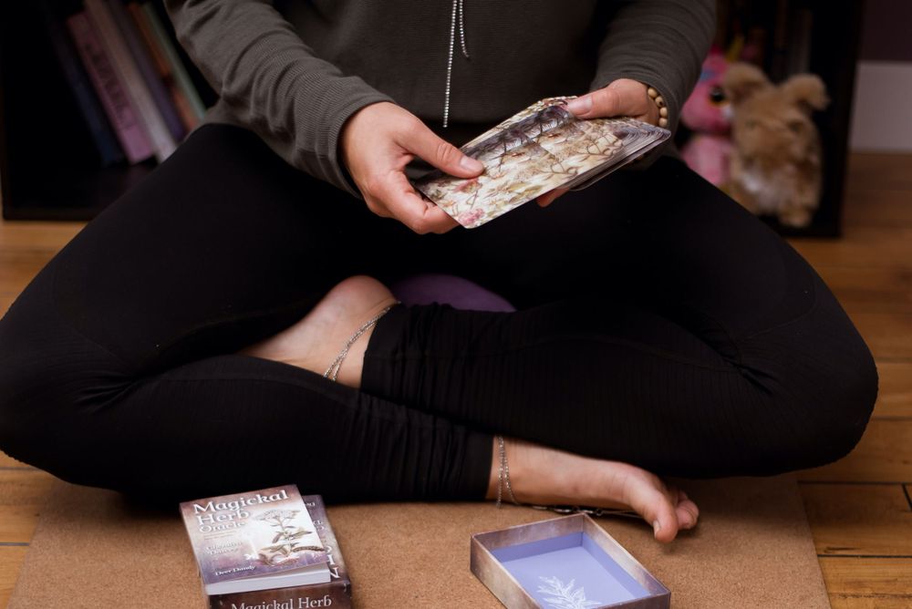 Hands holding cards while sitting cross-legged on wooden floor.