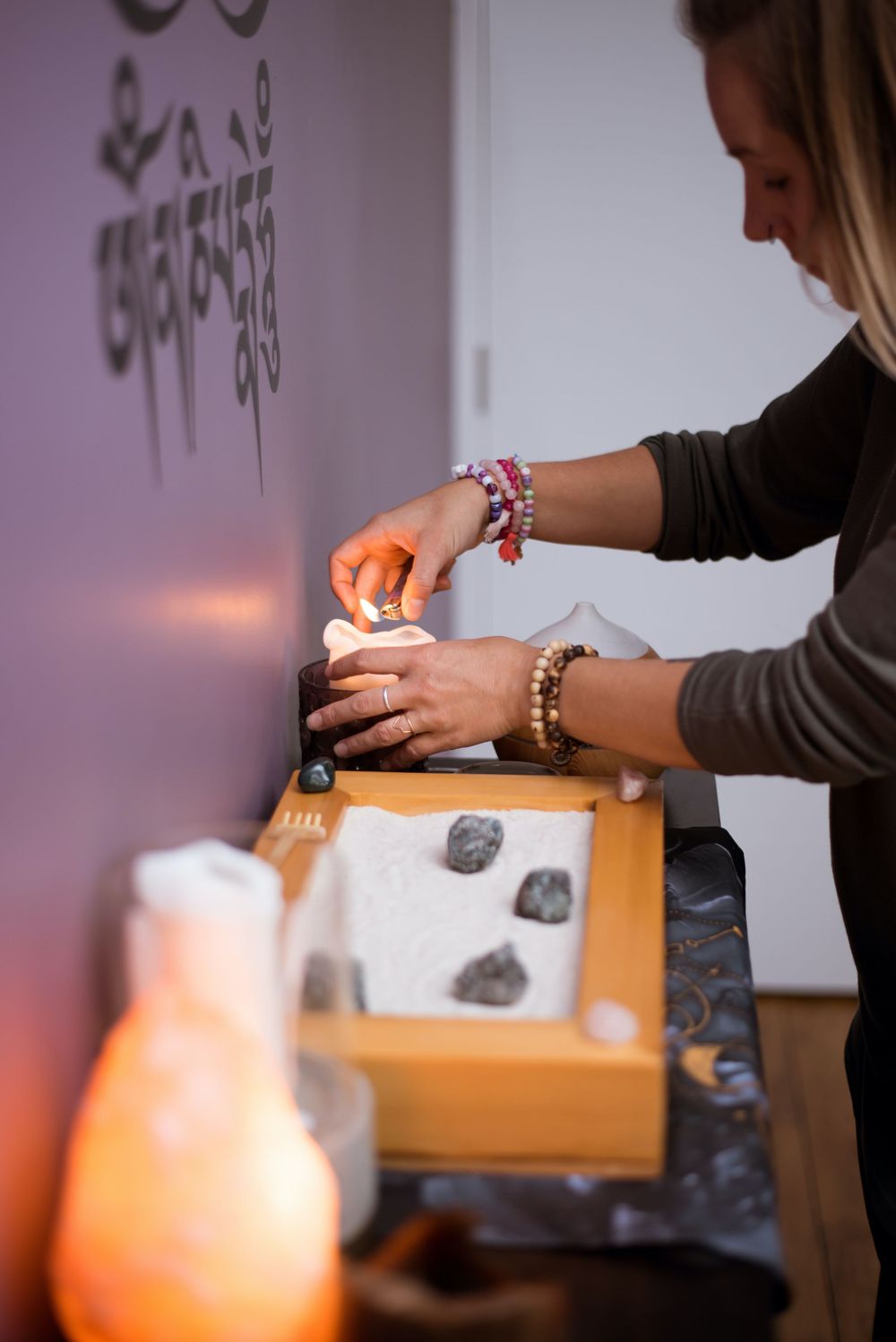 Hands placing items in wooden box with salt lamp glowing orange in foreground.