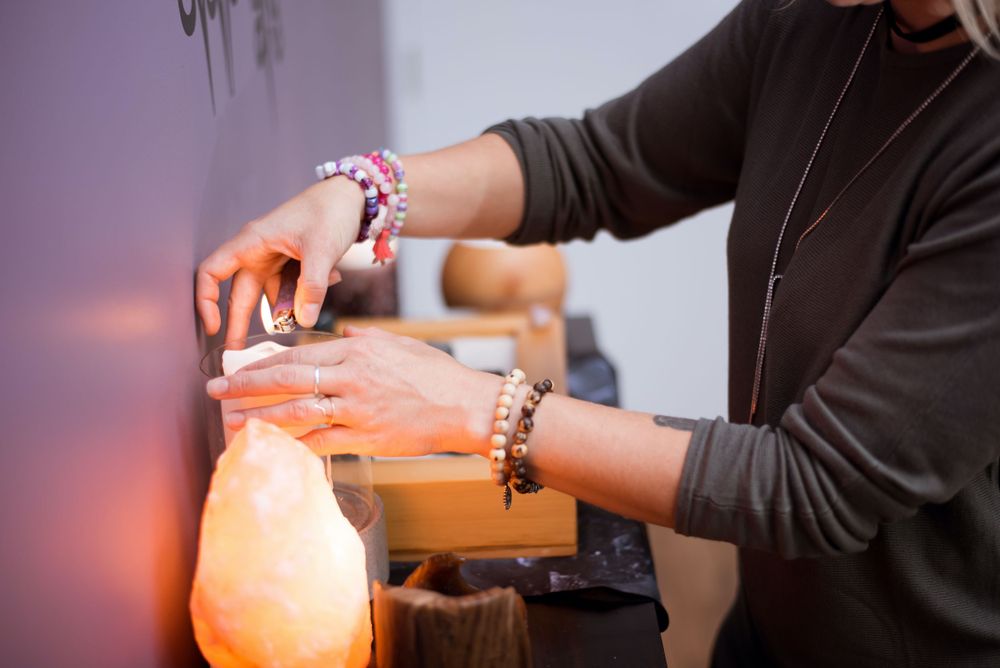 Hands wearing colorful bracelets reaching toward glowing orange salt lamp.