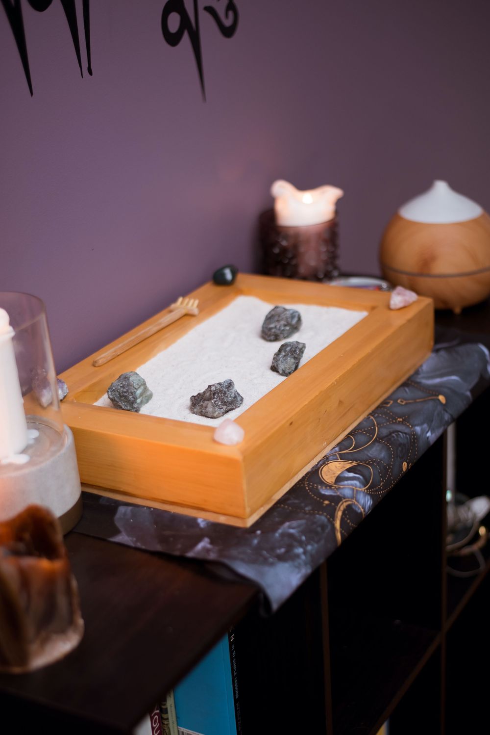 Orange wooden box filled with crystals and stones on dark surface with glowing candles and decorative elements.