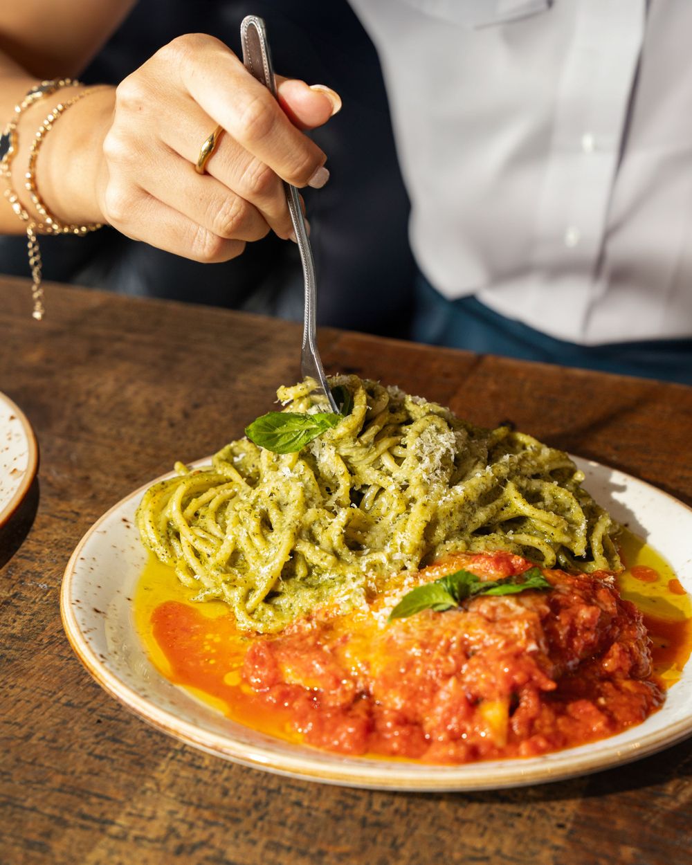 Plate of pesto pasta and meatballs in tomato sauce being served at a restaurant. Mtlshutter photography