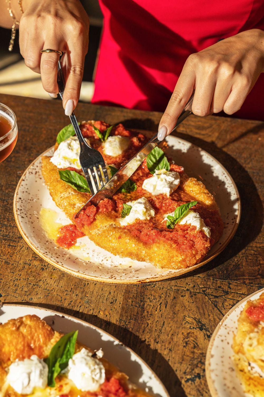 A golden breaded cutlet topped with red sauce, fresh mozzarella and basil on a ceramic plate. Mtlshutter photography