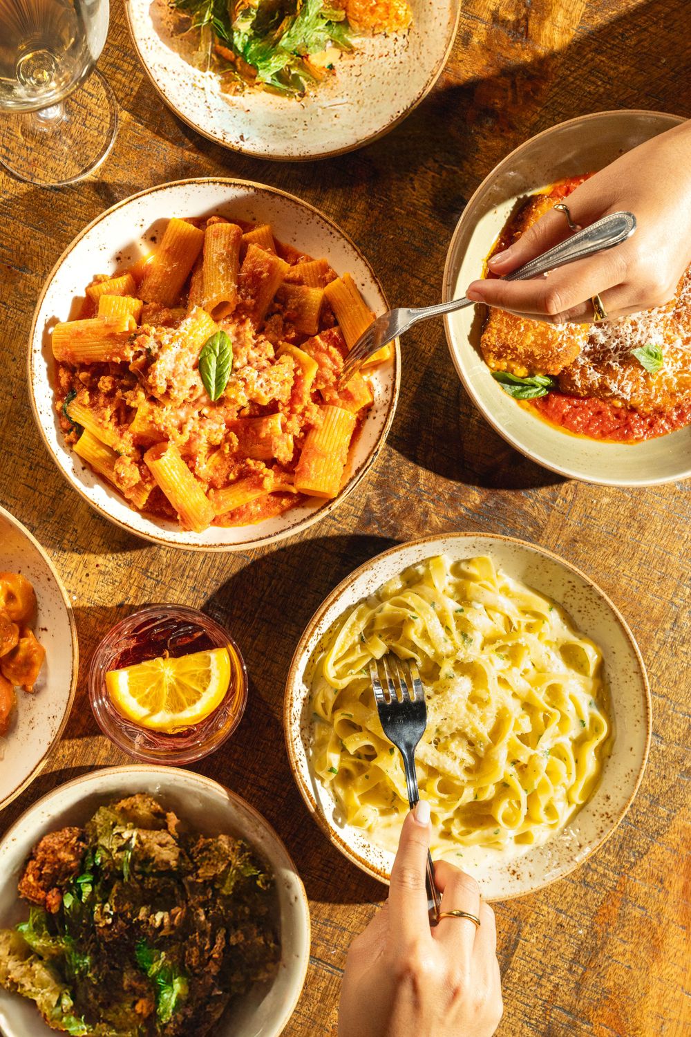 Overhead view of Italian dishes including pasta with cream sauce and spicy red sauce on a rustic wooden surface.Mtlshutter photography