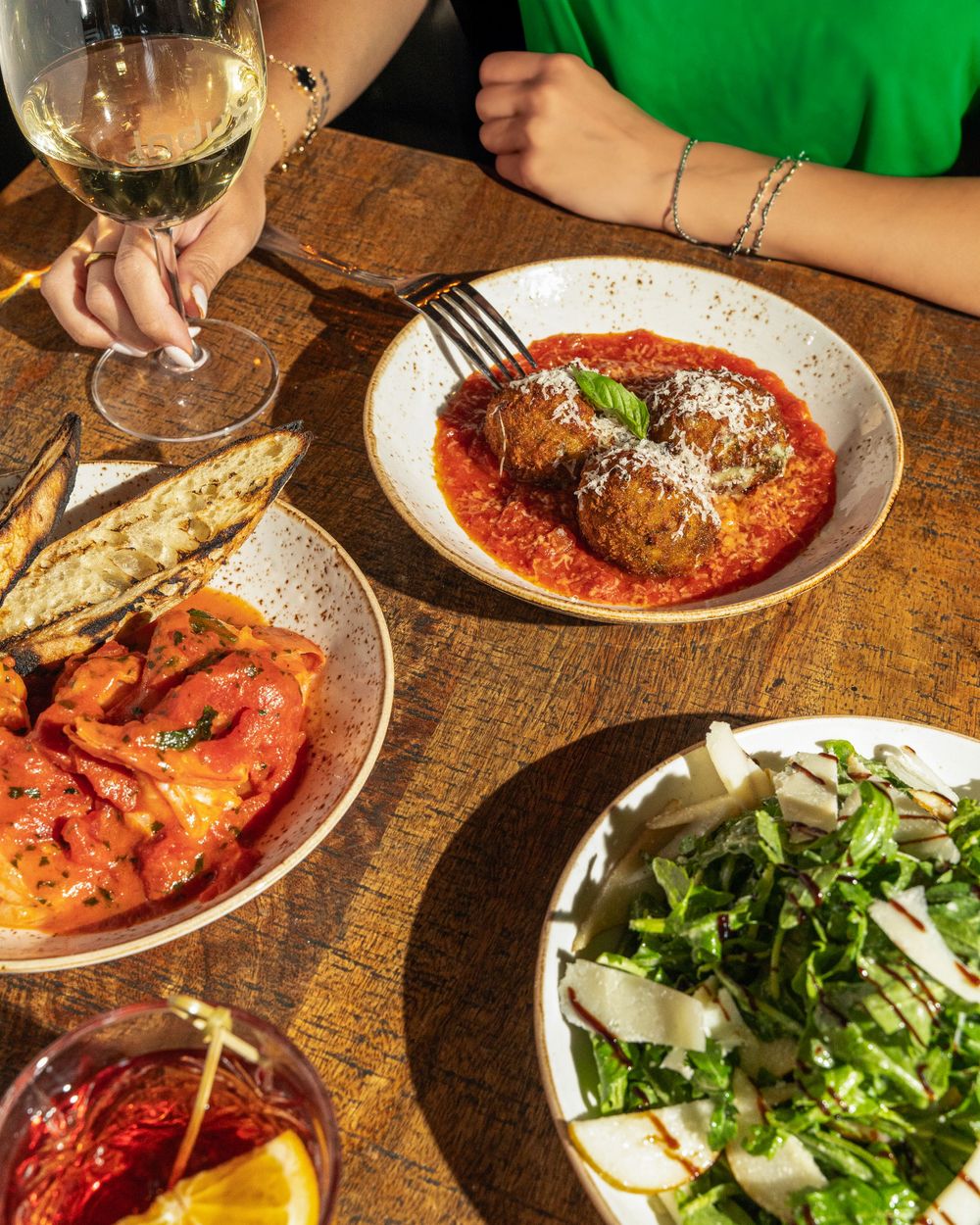 Italian dinner spread with meatballs, salad, and wine on a wooden table.Mtlshutter photography
